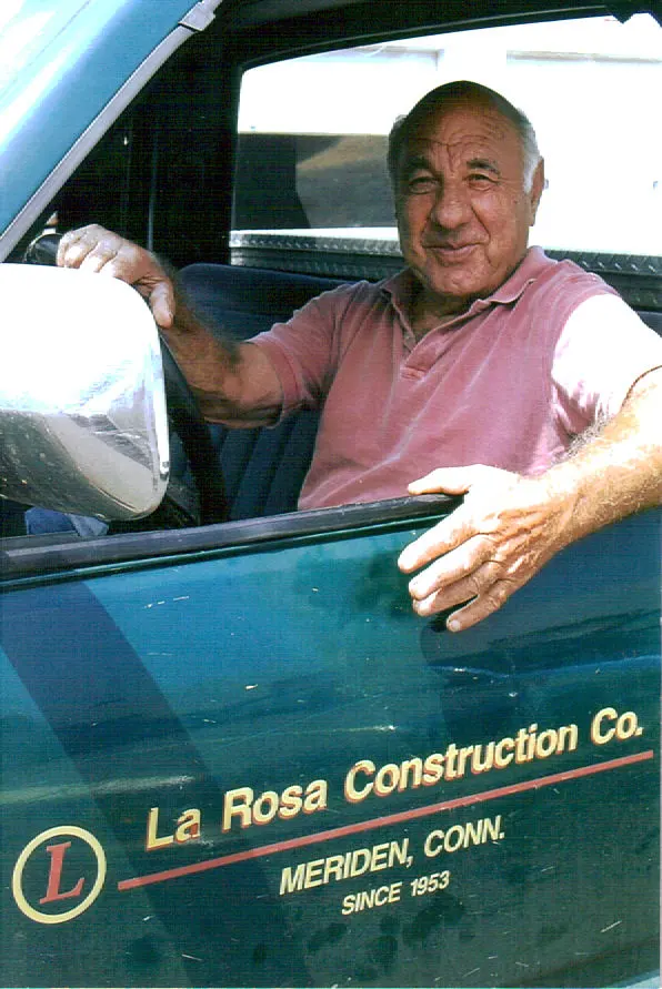 Joseph Salvatore LaRosa smiles while sitting in the driver&rsquo;s seat of a truck with the LaRosa Construction logo visible on the door.