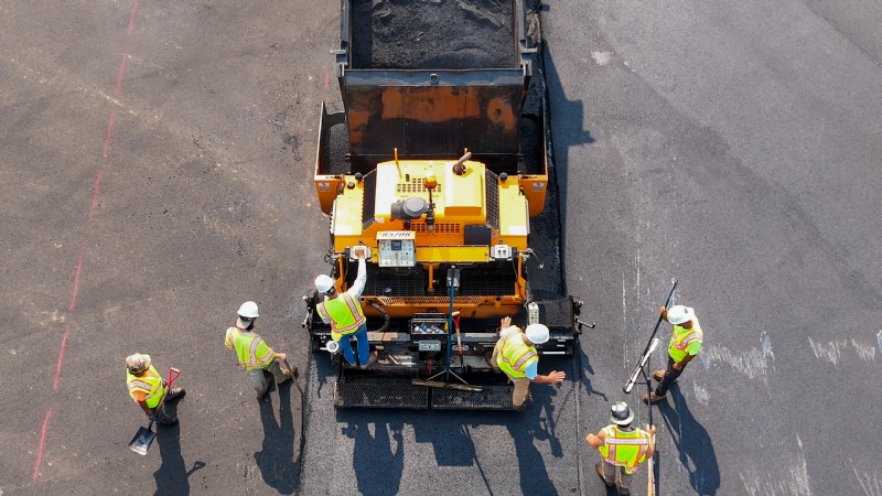 Aerial view of a dump truck and a crew working on the parking lot paving operation.