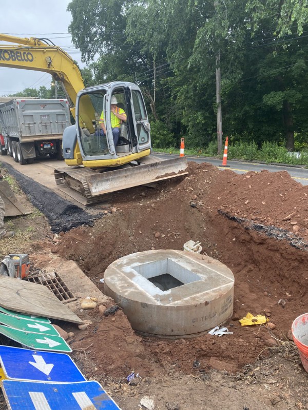 A crew worker operates an excavator while constructing a new sewer.