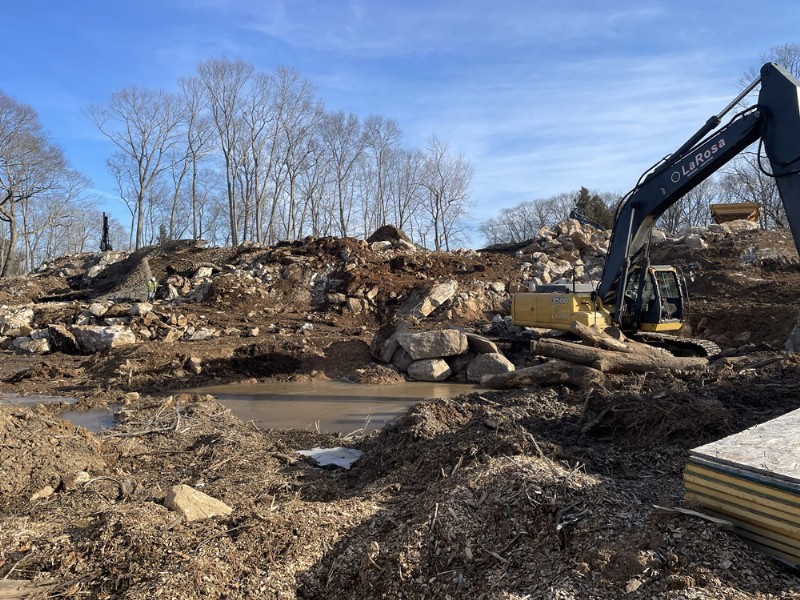 A LaRosa excavator moving soil and rocks on the construction site.