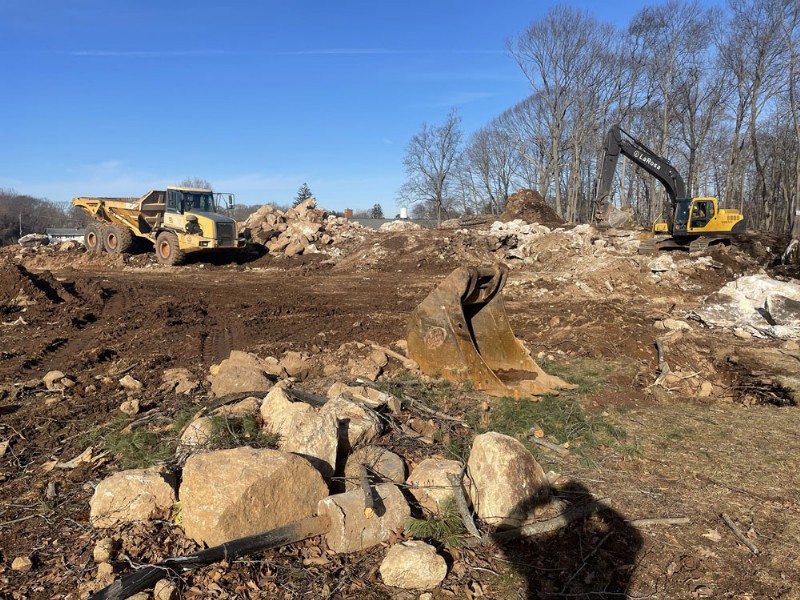 An excavator and a dump truck engaged in removing large rocks and debris from the construction site.