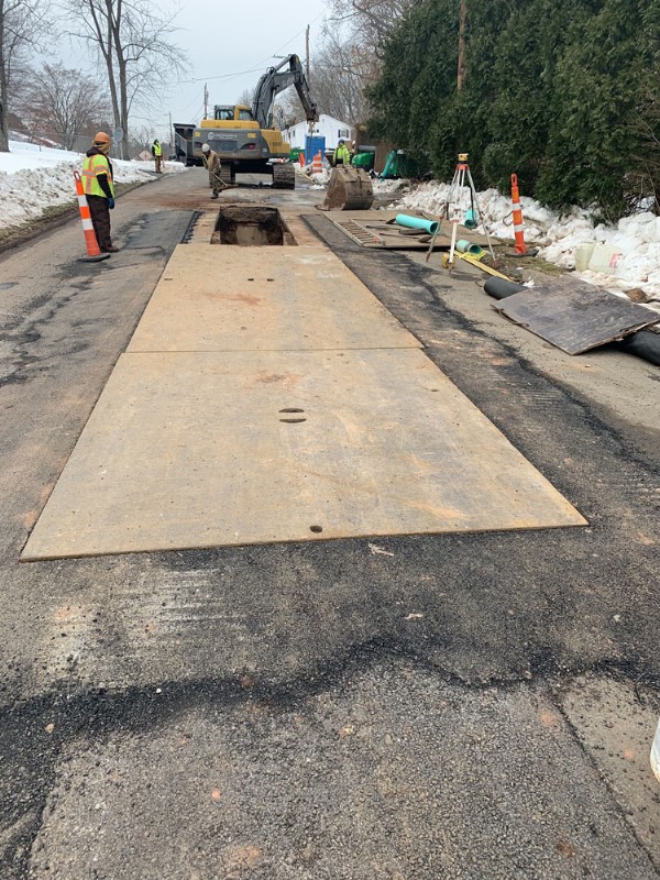 Steel road plates are laid to cover open trenches during construction.
