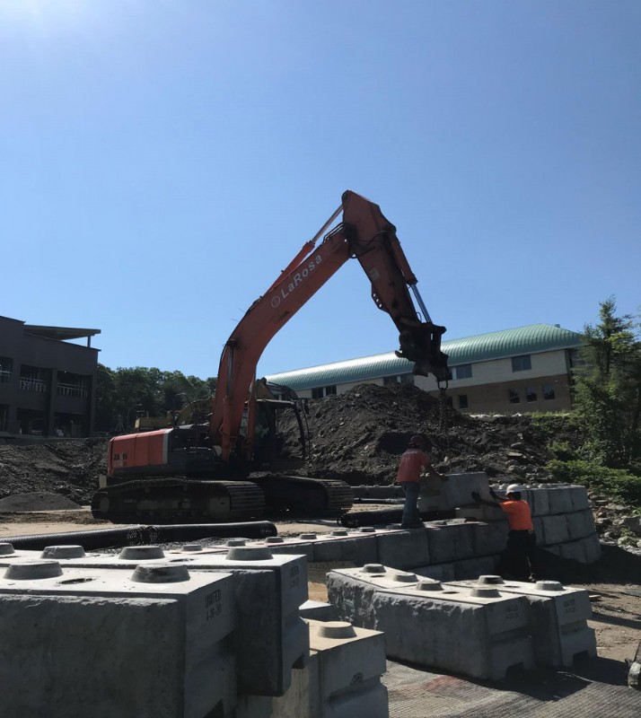 An excavator with the LaRosa logo clears and grades land during the construction project.