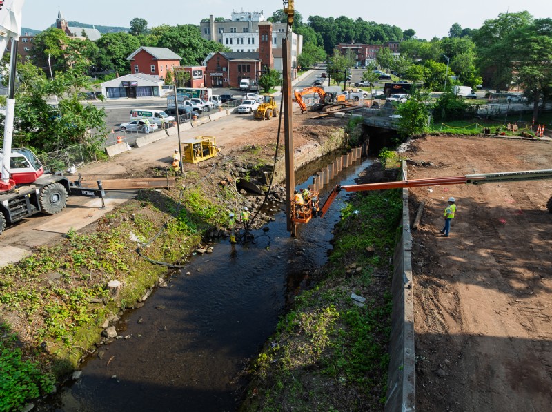 Crews installing steel sheet piling for water retention during the bridge replacement.