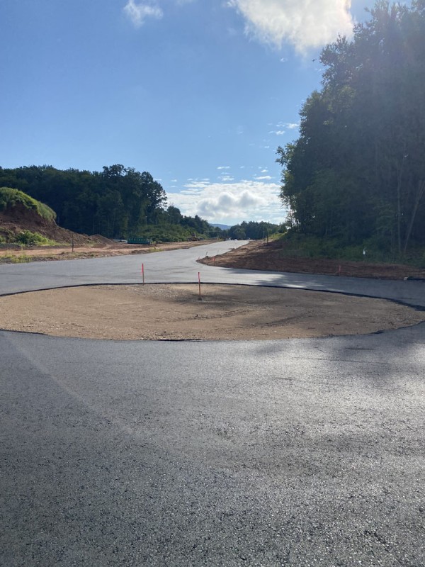 Construction site with a newly paved circular road and a cleared area at center.